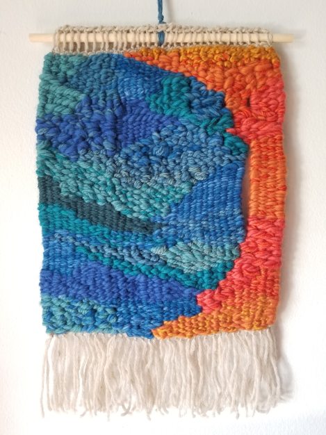 colorful, textured woven artwork - mainly blues and greens with a narrow section of reds and oranges on the right side